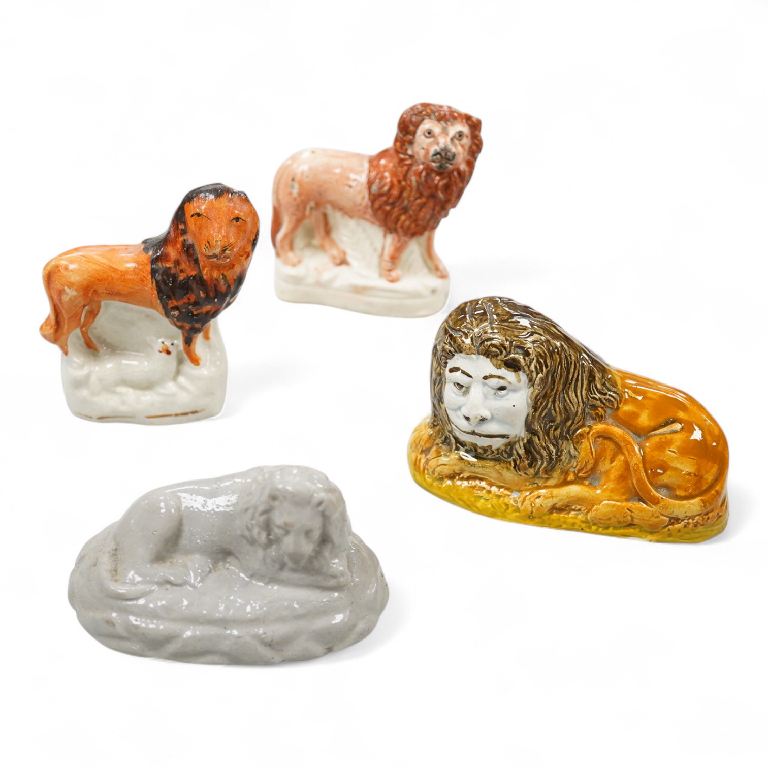 A rare Staffordshire Pearlware model of a recumbent lion, c.1810, and three Staffordshire pottery models of lions, mid 19th century, largest 11cm wide